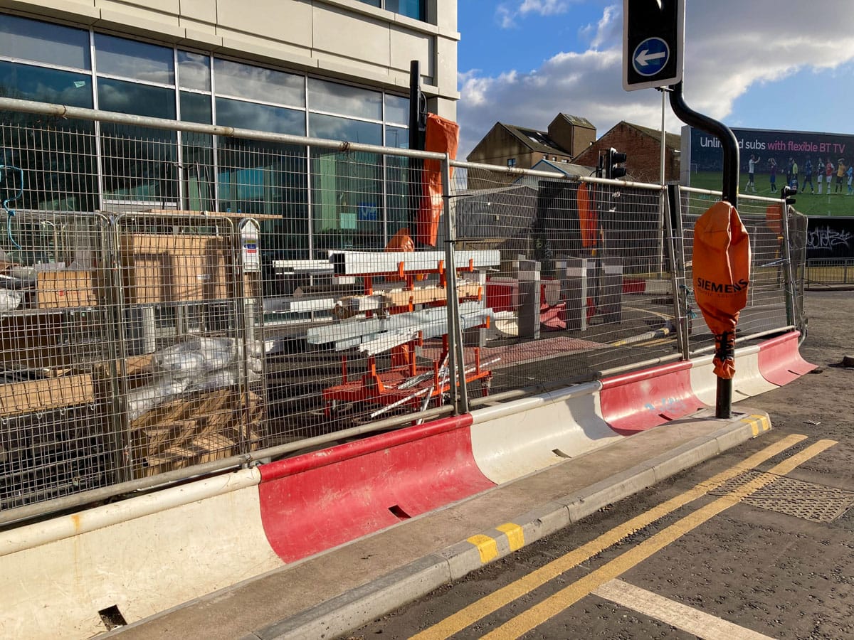 Photo of building materials stored in fenced off cycle lane on West St